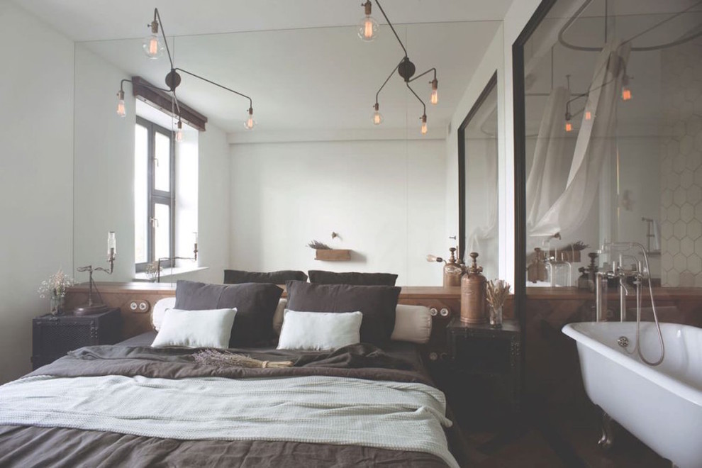 Immagine di una piccola camera matrimoniale industriale con pareti verdi, pavimento in legno massello medio e pavimento marrone