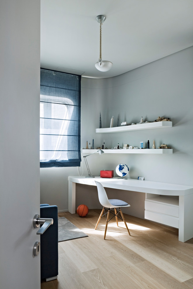 Exempel på ett mellanstort modernt könsneutralt barnrum kombinerat med skrivbord, med blå väggar och ljust trägolv