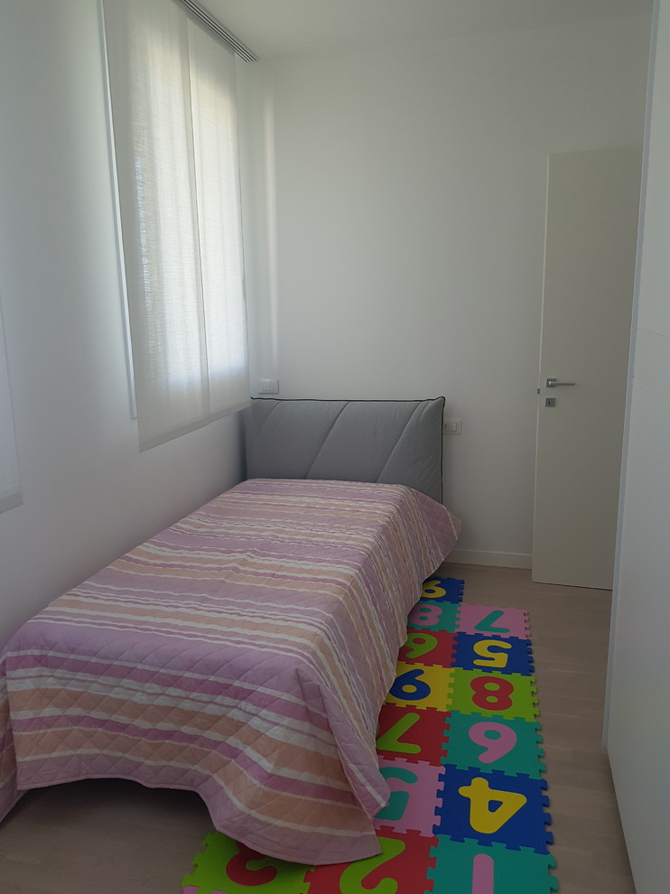 Diseño de dormitorio infantil de 4 a 10 años moderno pequeño con paredes blancas, suelo de madera clara y suelo beige