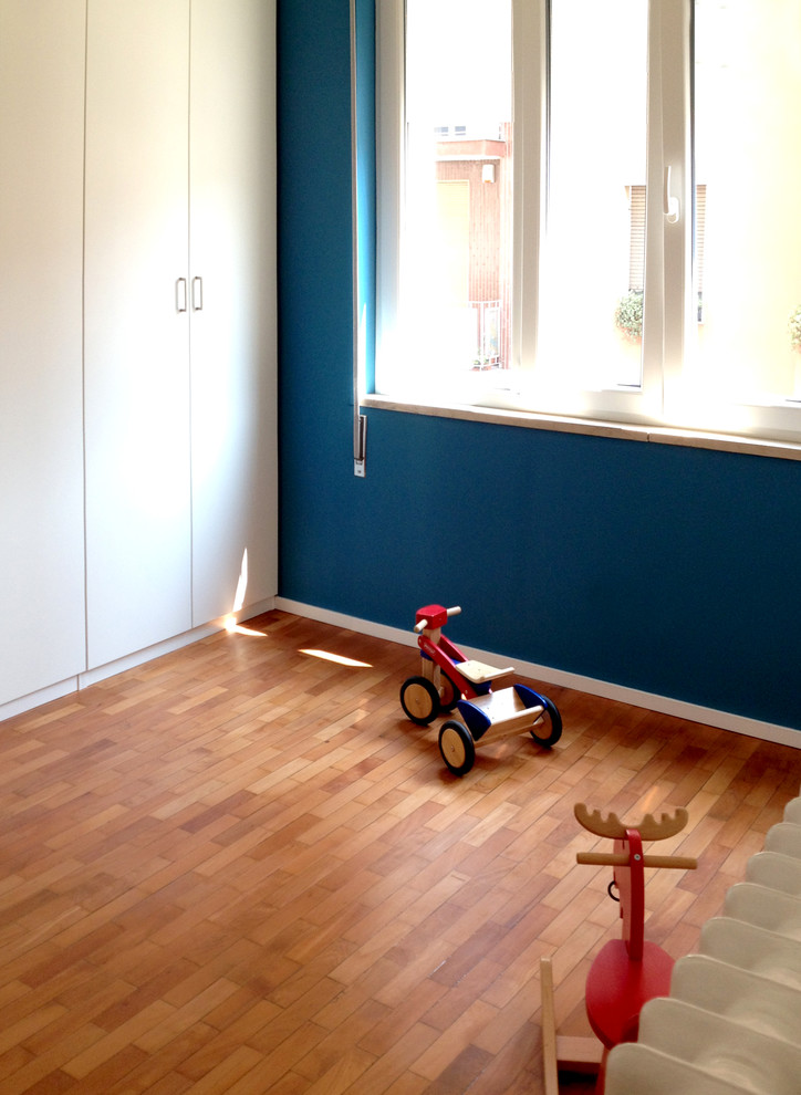 Inredning av ett modernt barnrum kombinerat med sovrum, med blå väggar och mellanmörkt trägolv