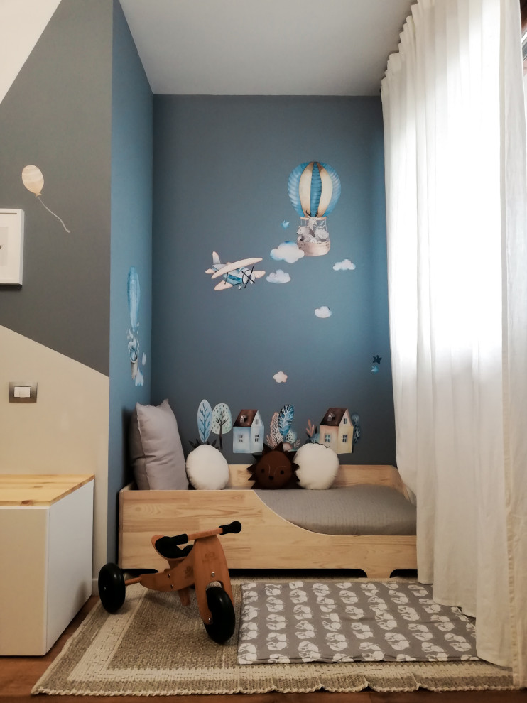 Ispirazione per una cameretta per bambini da 1 a 3 anni minimal di medie dimensioni con pareti blu e parquet chiaro