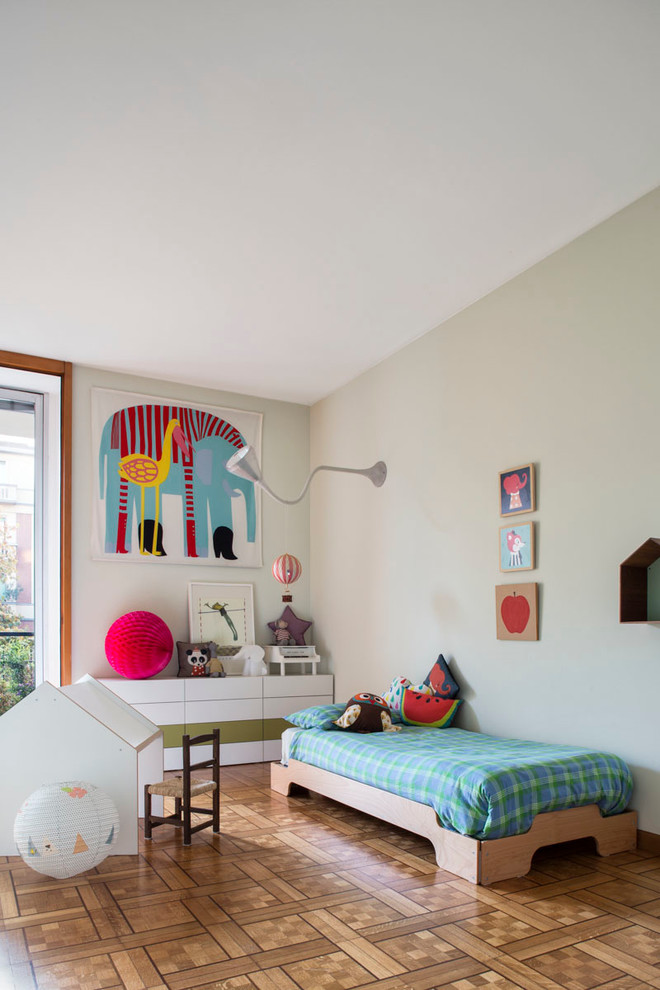 Contemporary gender neutral children’s room in Milan with medium hardwood flooring and grey walls.