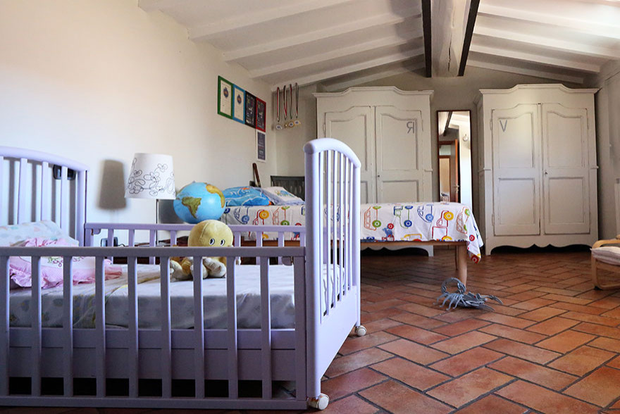Mittelgroßes Landhaus Kinderzimmer mit blauer Wandfarbe, Terrakottaboden, orangem Boden und freigelegten Dachbalken in Sonstige