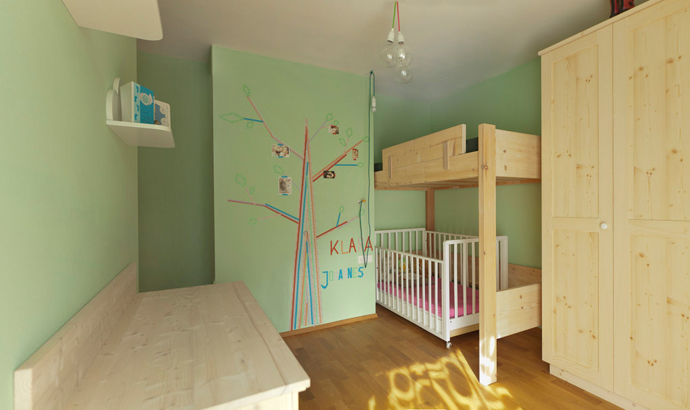 Idée de décoration pour une petite chambre d'enfant minimaliste avec un mur vert et un sol en bois brun.