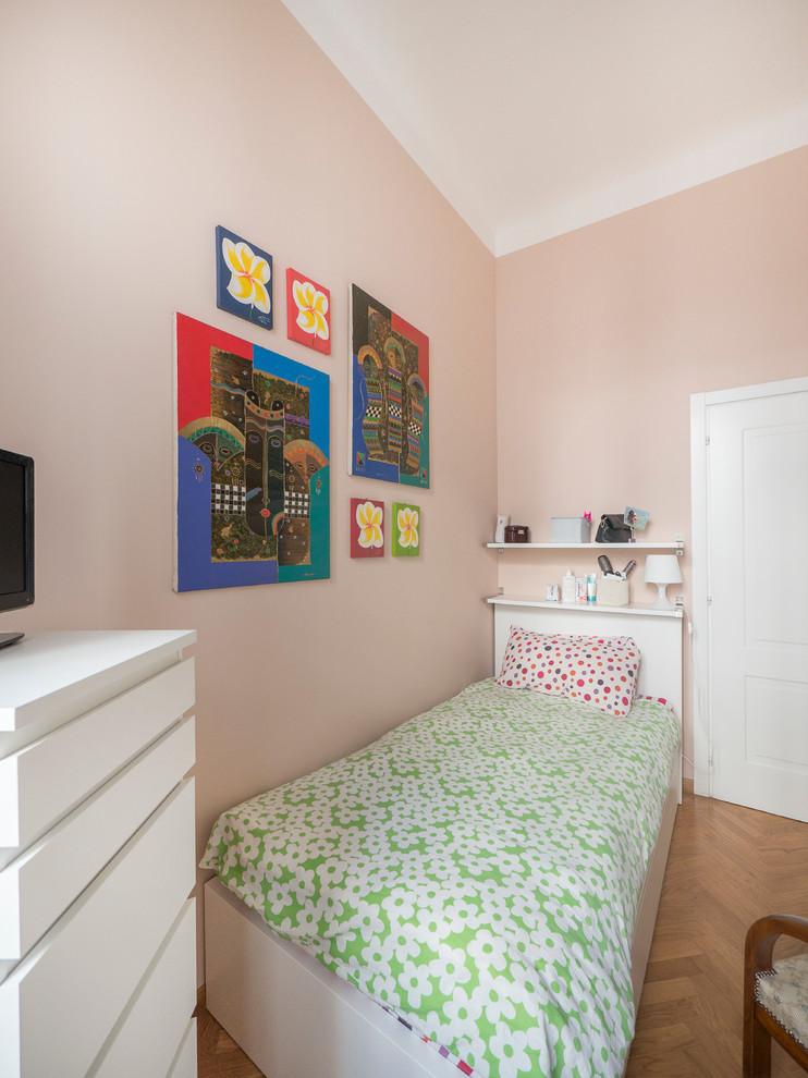Cette photo montre une petite chambre d'enfant tendance avec un mur rose et parquet clair.