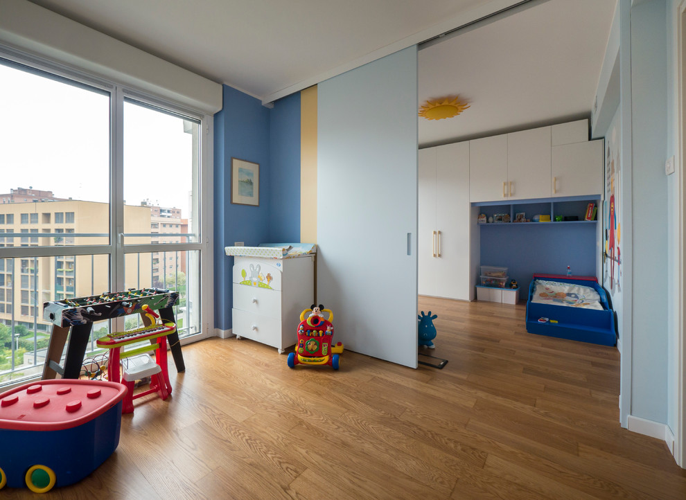 This is an example of a medium sized contemporary children’s room for boys in Milan with blue walls and light hardwood flooring.