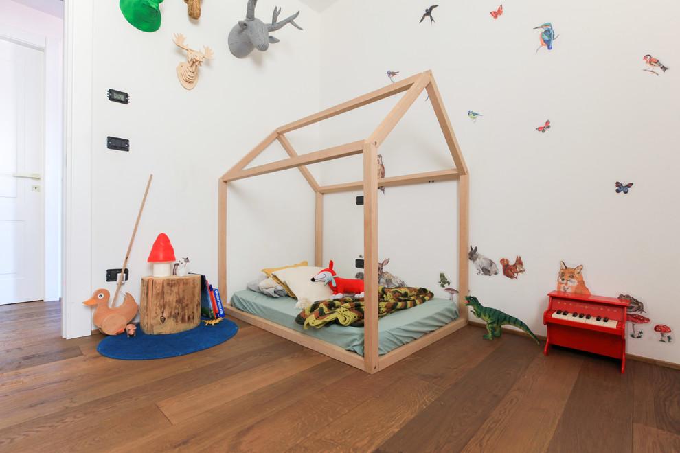 Foto di una cameretta per bambini da 1 a 3 anni mediterranea con pareti bianche, pavimento in legno massello medio e pavimento marrone