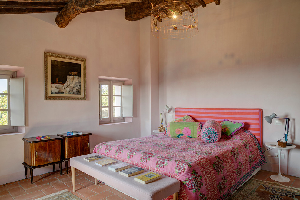 This is an example of a mediterranean teen’s room for girls in Florence with pink walls, terracotta flooring, orange floors and exposed beams.