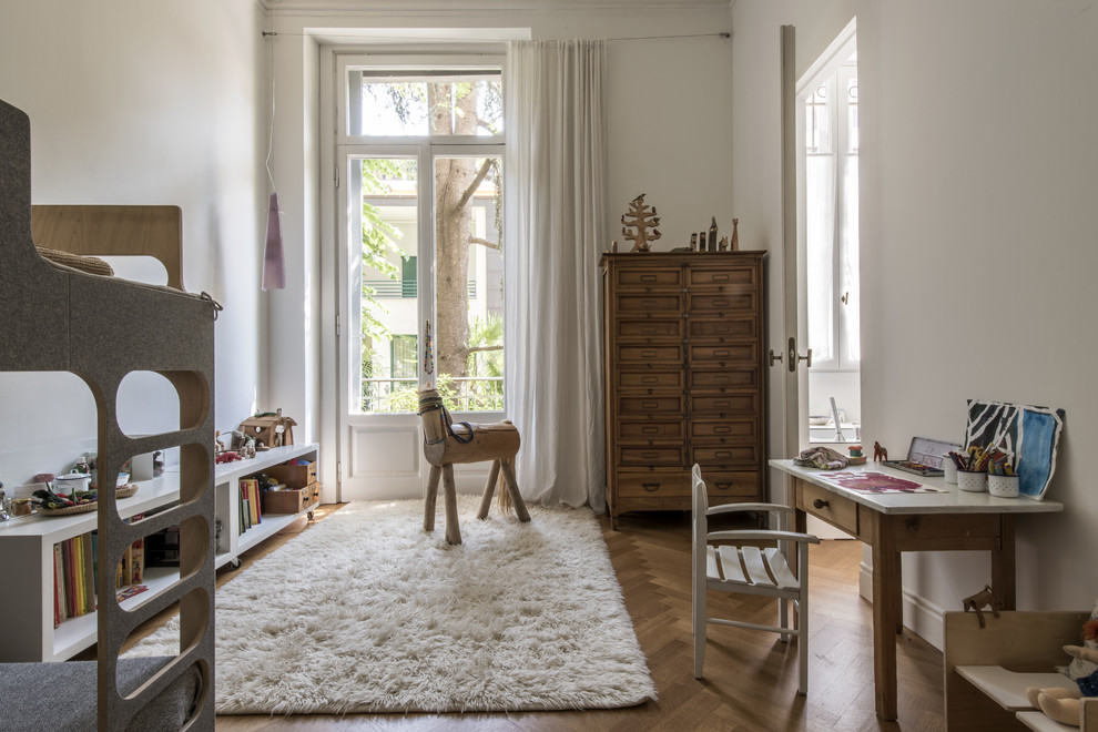 Ispirazione per una cameretta per bambini da 4 a 10 anni scandinava di medie dimensioni con pareti bianche, pavimento in legno massello medio e pavimento marrone