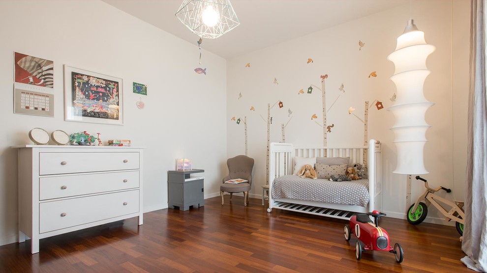 Skandinavisk inredning av ett mellanstort könsneutralt småbarnsrum kombinerat med lekrum, med mörkt trägolv och vita väggar