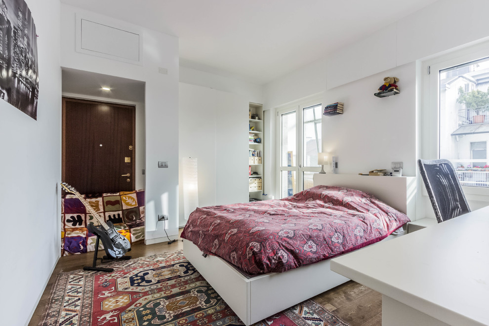 Esempio di una piccola cameretta per bambini minimal con pareti bianche, pavimento in legno massello medio e pavimento marrone