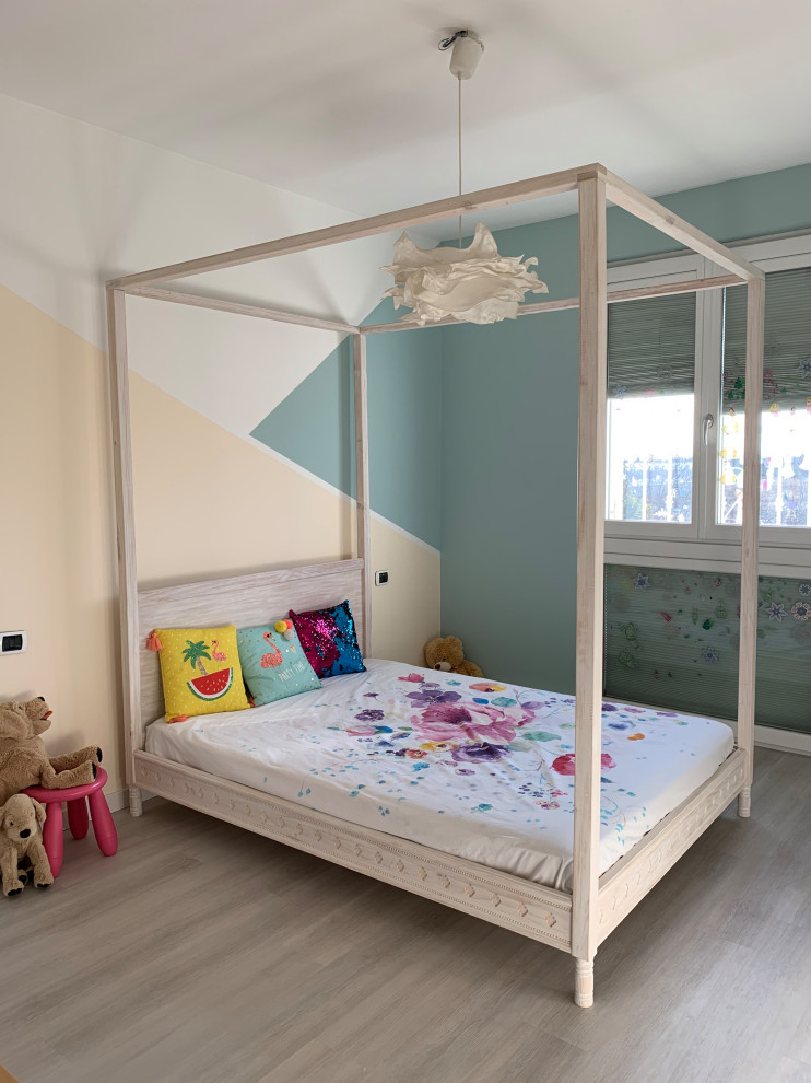 This is an example of a medium sized bohemian children’s room for girls in Milan with laminate floors and grey floors.