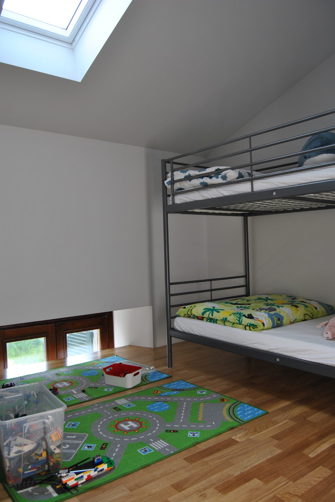 This is an example of a small contemporary children’s room in Milan with white walls, light hardwood flooring and beige floors.