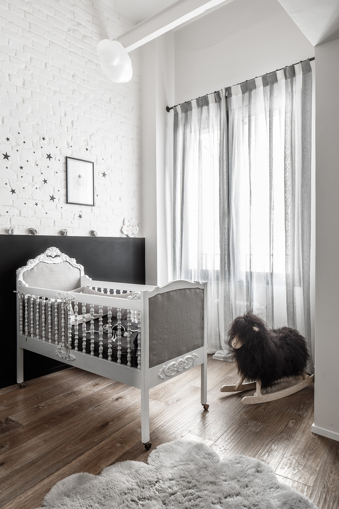 Photo of an eclectic nursery in Other with white walls, medium hardwood flooring and brown floors.