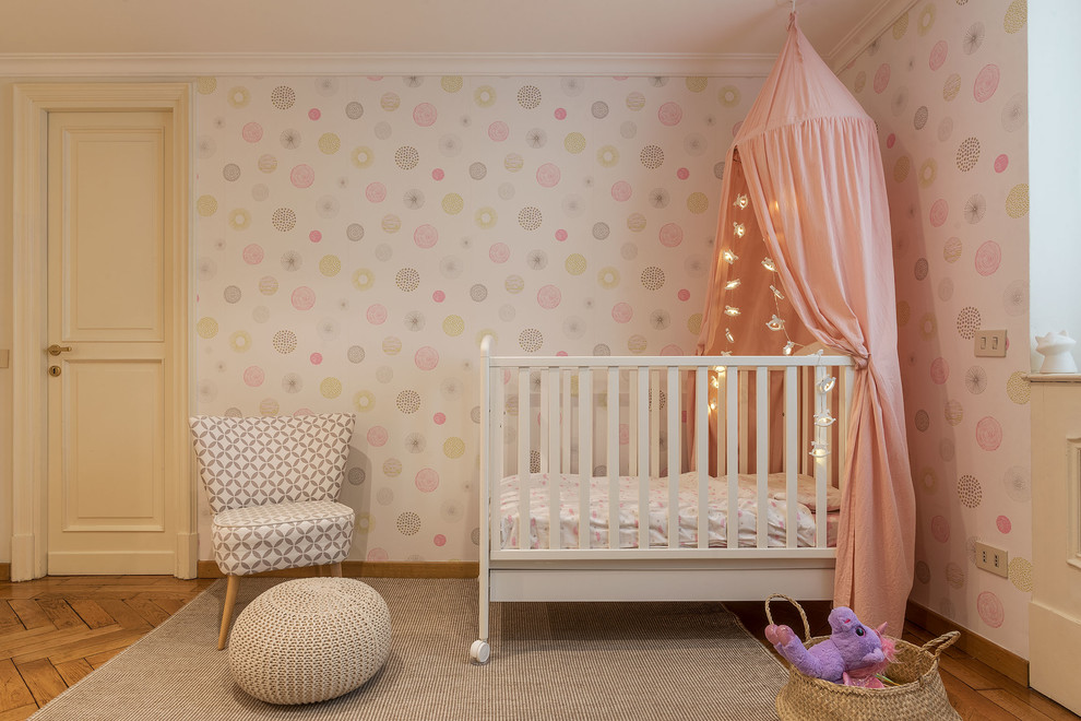Immagine di una cameretta per neonata nordica con pareti rosa
