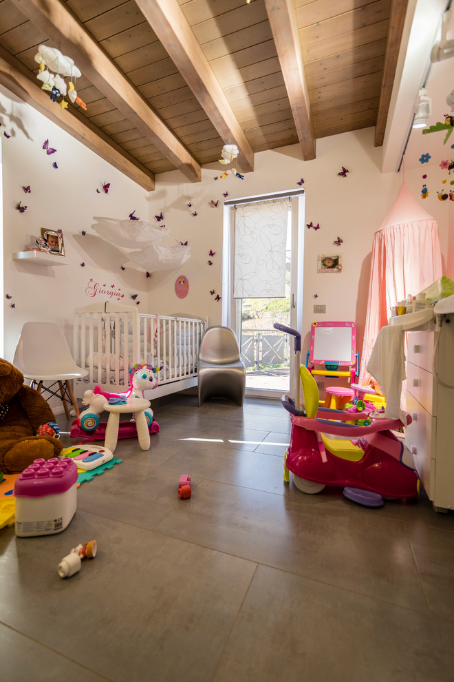 Foto di una piccola cameretta per neonata minimal con pareti bianche, pavimento in gres porcellanato e pavimento grigio