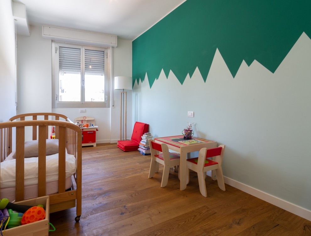 Diseño de habitación de bebé contemporánea con paredes multicolor y suelo de madera en tonos medios