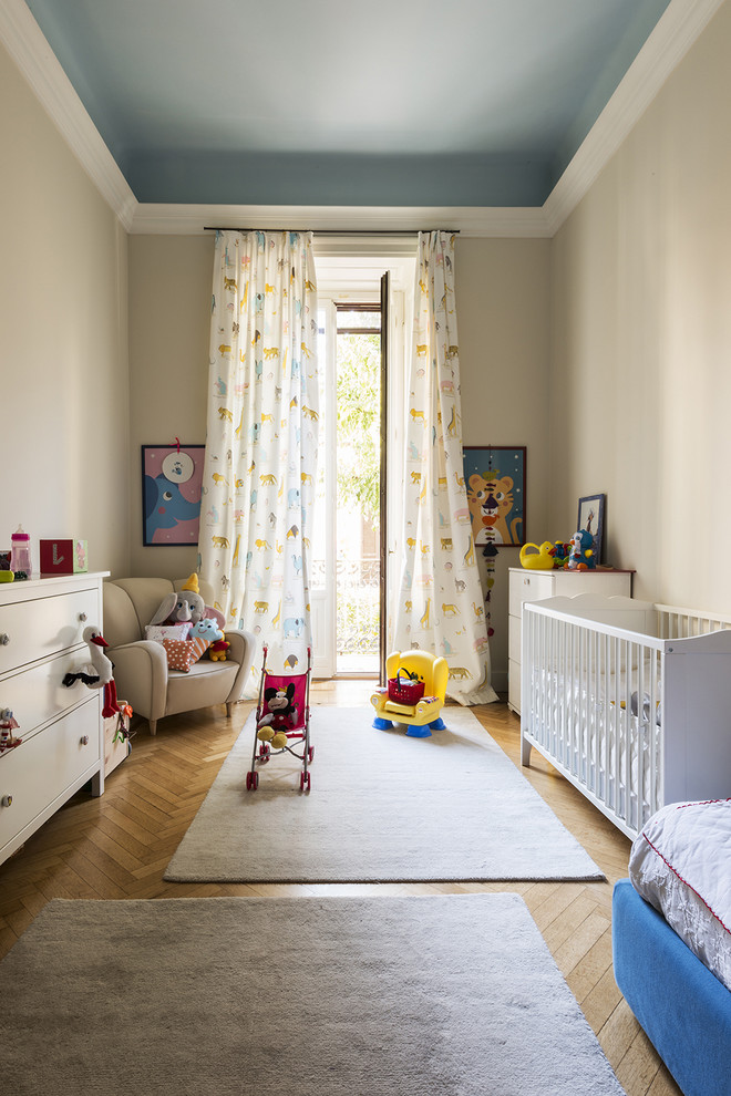 Foto di una cameretta per neonata chic di medie dimensioni con pareti beige, pavimento in legno massello medio e pavimento beige