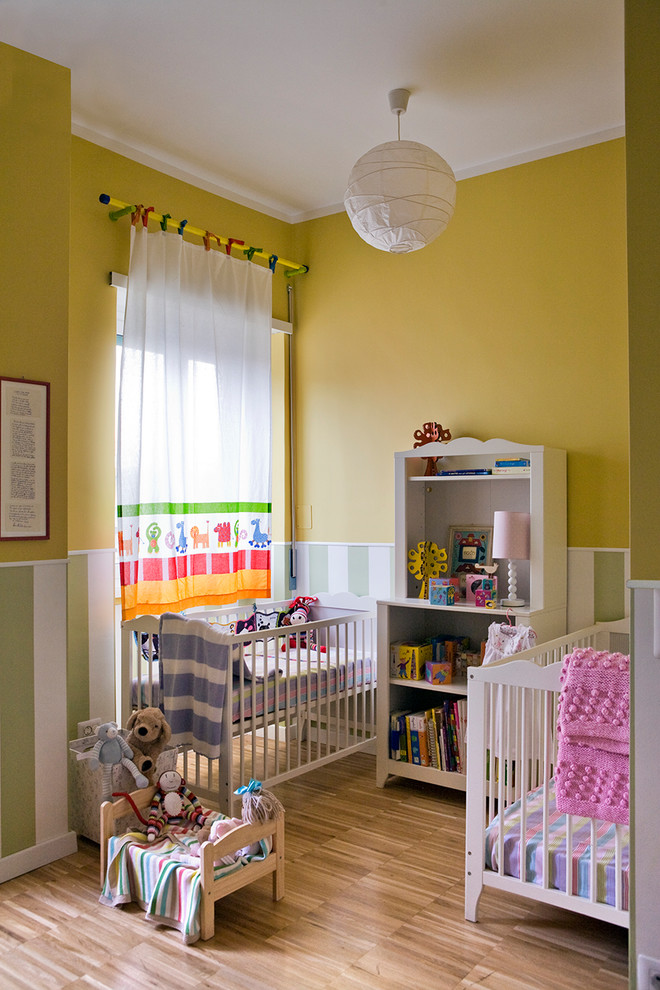 Inspiration för ett nordiskt könsneutralt babyrum, med gula väggar och laminatgolv
