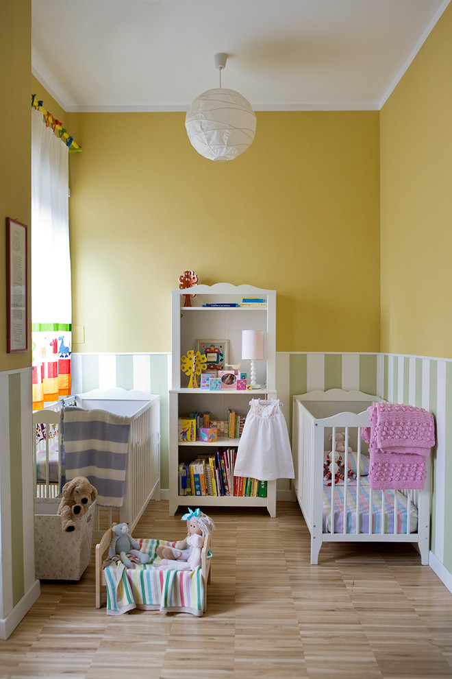Cette photo montre une chambre de bébé neutre chic de taille moyenne avec un mur jaune, un sol en bois brun et un sol beige.