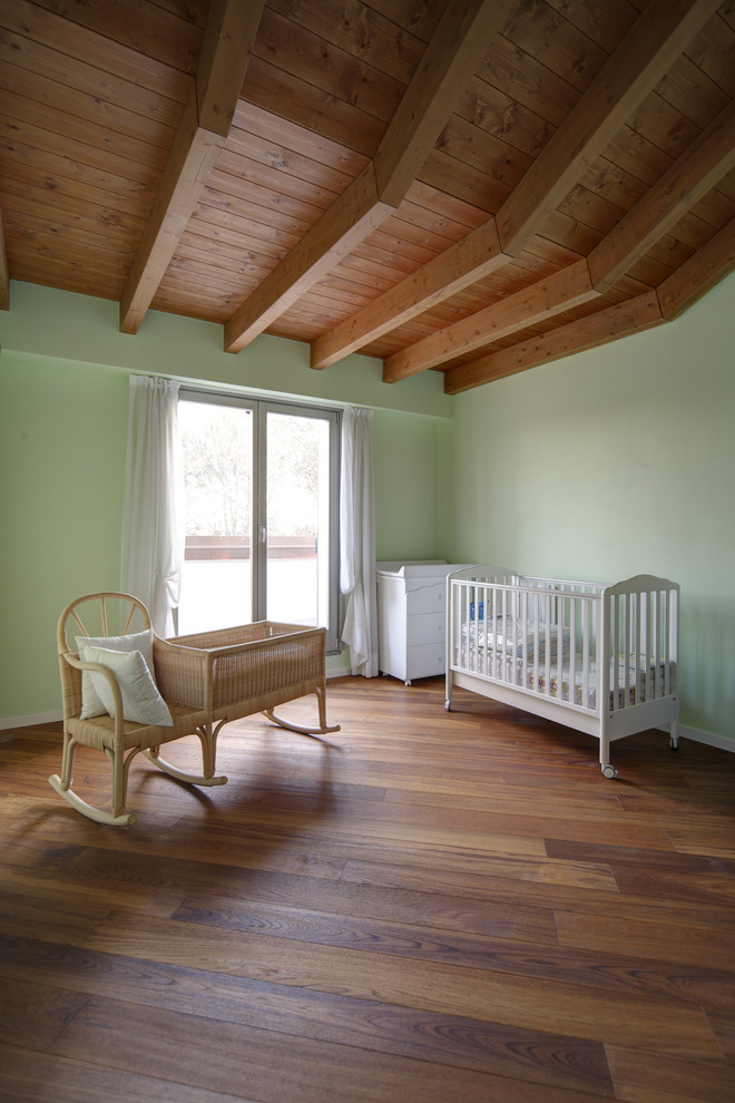 Esempio di una cameretta per neonati neutra country di medie dimensioni con pareti verdi e pavimento in legno massello medio
