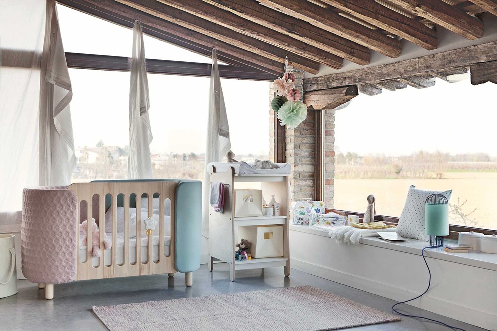 Photo of a medium sized scandi nursery for girls in Milan with white walls, concrete flooring and grey floors.