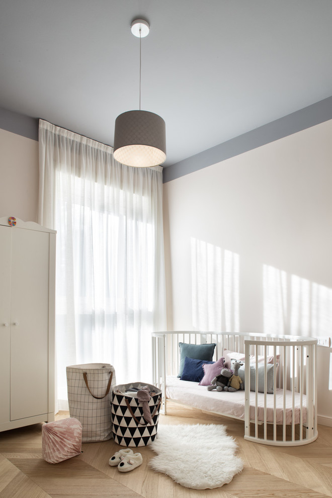 Imagen de habitación de bebé neutra nórdica con paredes blancas, suelo de madera clara y suelo beige