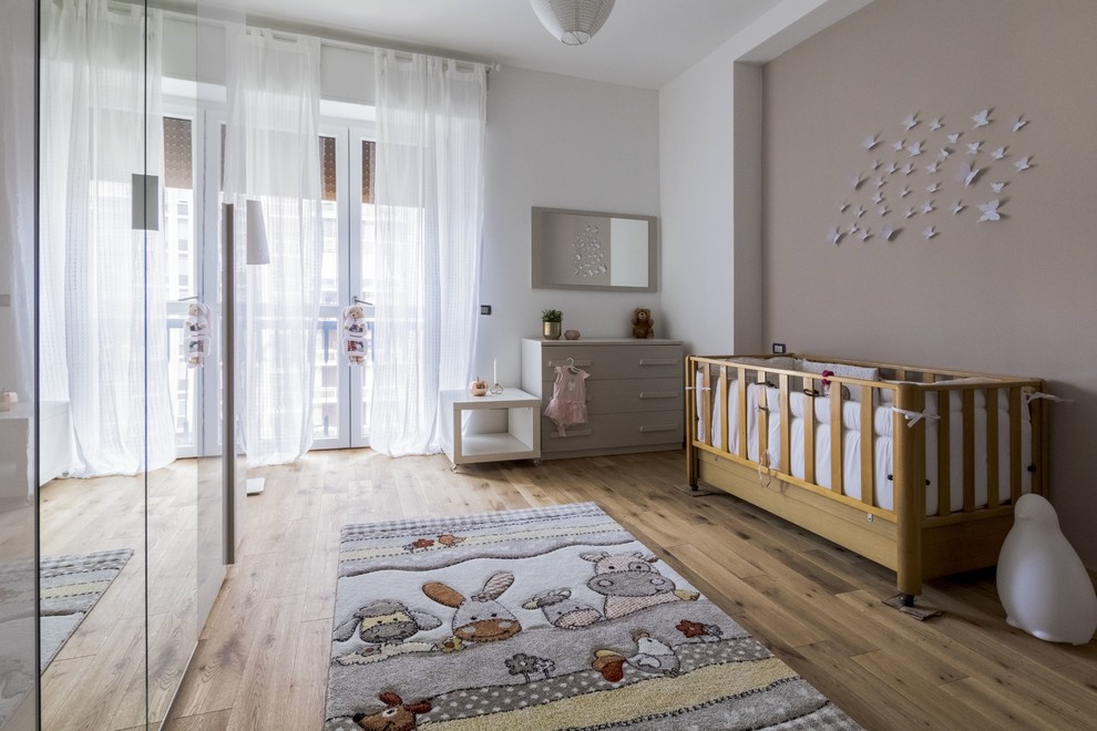 Réalisation d'une chambre de bébé neutre tradition avec un mur beige, un sol en bois brun et un sol marron.