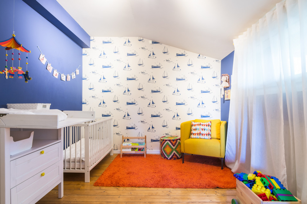 Immagine di una grande cameretta per neonati contemporanea con pareti blu, pavimento in legno massello medio e pavimento marrone