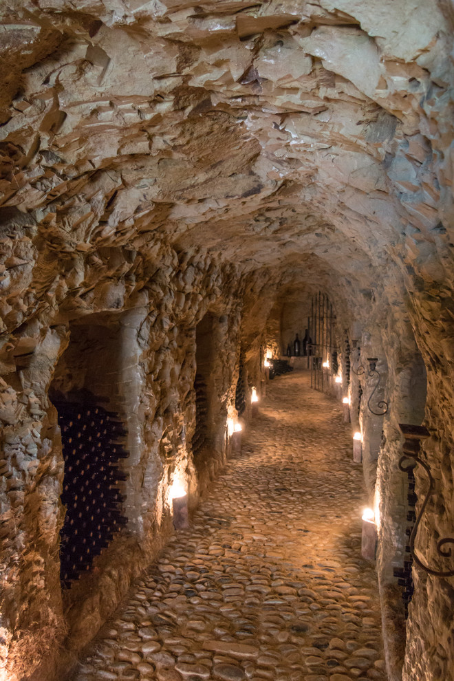 Exemple d'une grande cave à vin nature avec un sol en calcaire et un présentoir.