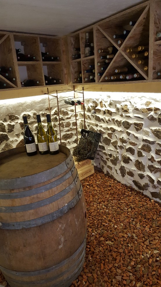 Foto på en mellanstor lantlig vinkällare, med klinkergolv i terrakotta, vinställ med diagonal vinförvaring och rött golv