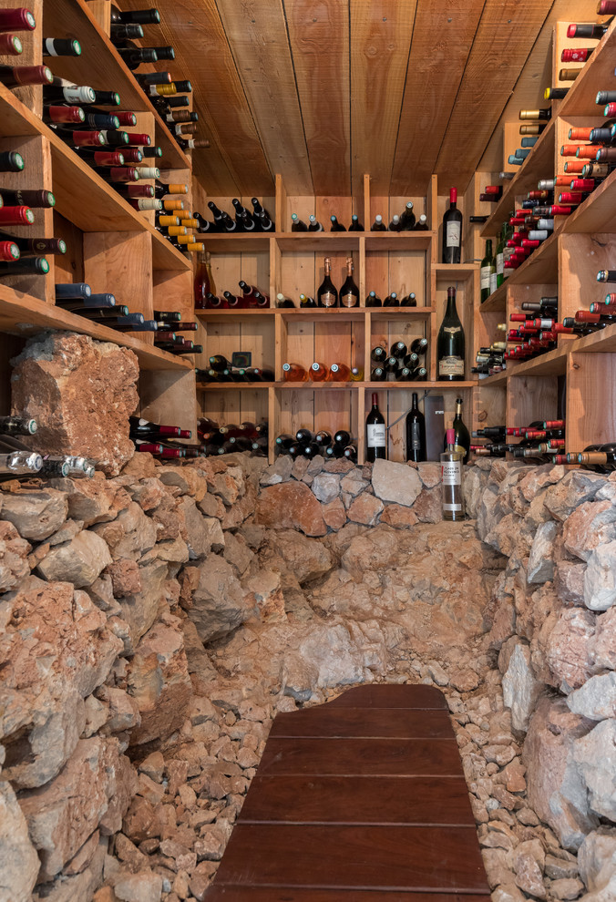 Inspiration pour une cave à vin méditerranéenne avec parquet foncé, des casiers et un sol marron.