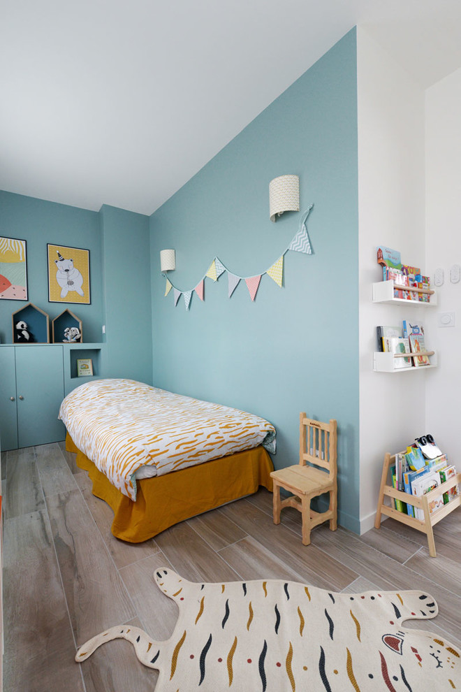 Design ideas for a scandinavian gender neutral toddler’s room in Paris with blue walls and beige floors.