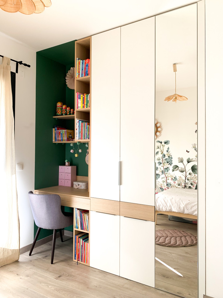 Esempio di una cameretta per bambini da 4 a 10 anni minimalista di medie dimensioni con pareti verdi, pavimento in laminato, pavimento beige e carta da parati