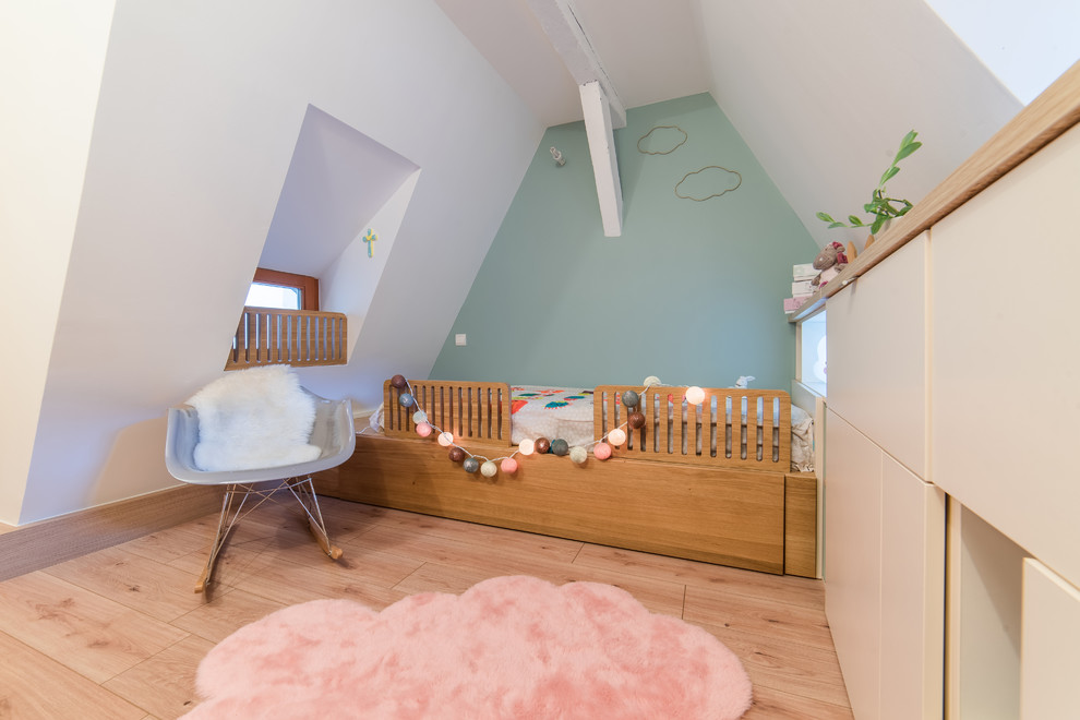 Minimalistisk inredning av ett litet flickrum kombinerat med sovrum, med blå väggar och laminatgolv
