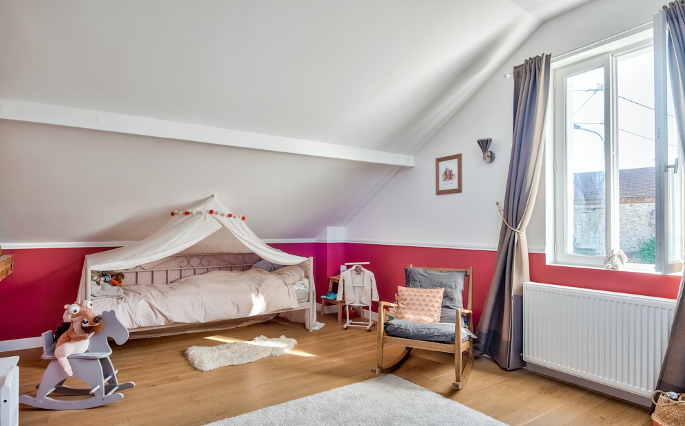 This is an example of a traditional toddler’s room for girls in Paris with white walls and light hardwood flooring.
