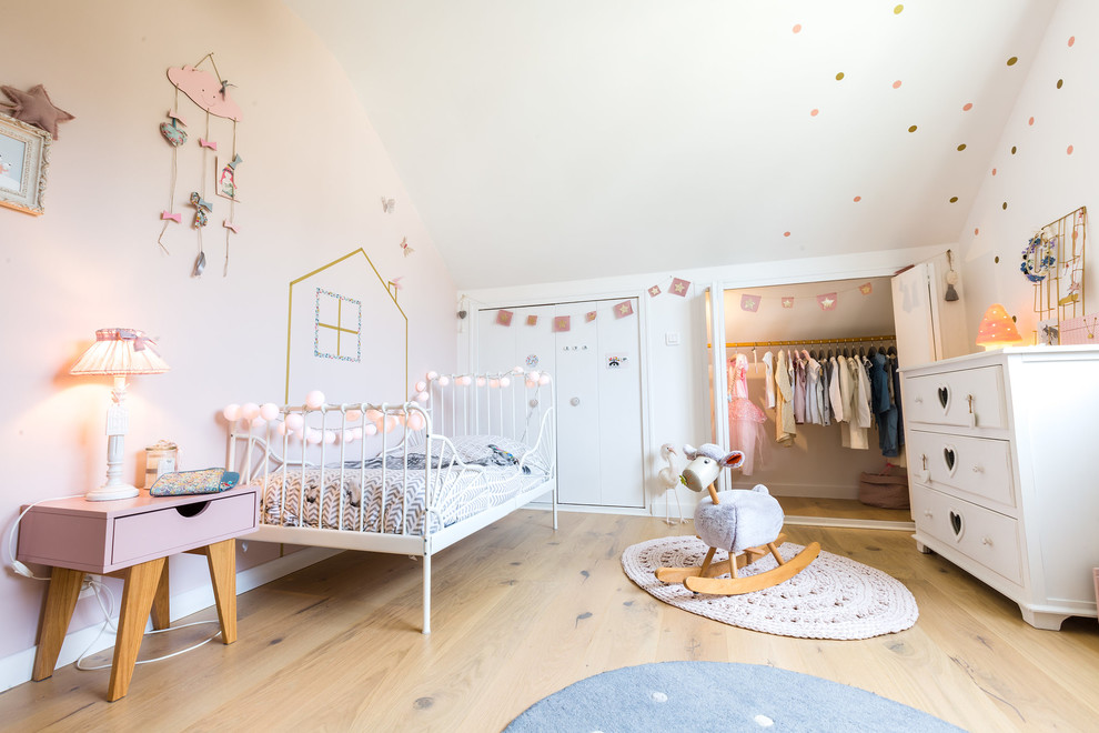 This is an example of a scandi toddler’s room for girls in Nantes with white walls, light hardwood flooring and beige floors.