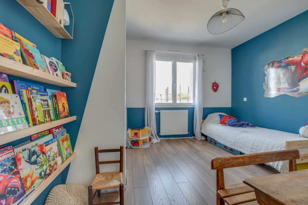 На фото: детская среднего размера в стиле модернизм с спальным местом, синими стенами, полом из ламината и коричневым полом для ребенка от 4 до 10 лет, мальчика с