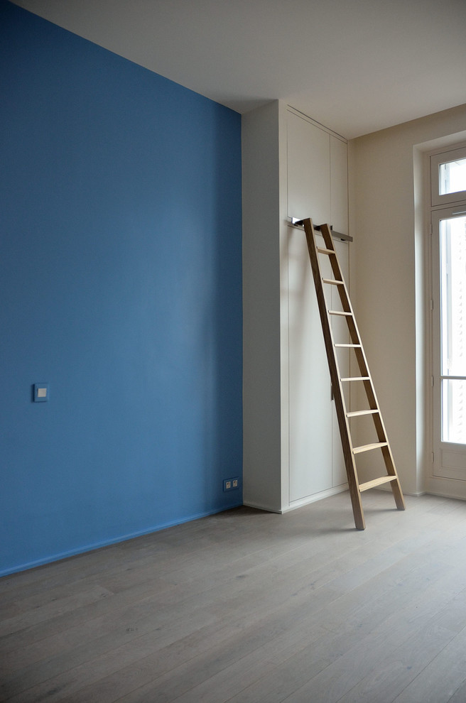 Modelo de dormitorio infantil contemporáneo de tamaño medio con paredes azules, suelo de madera clara y suelo gris