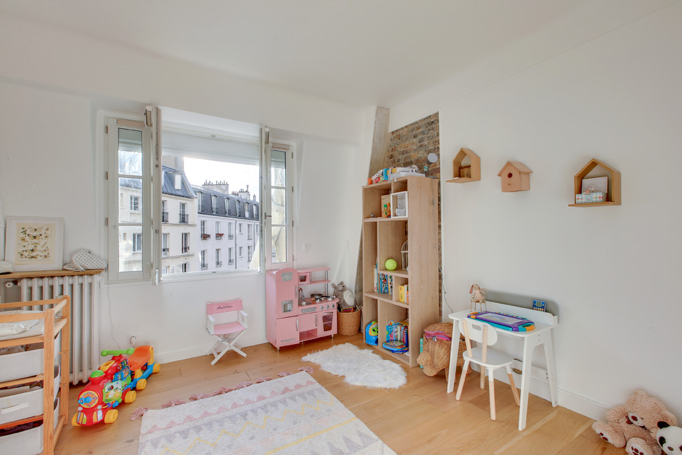 Modelo de dormitorio infantil de 4 a 10 años contemporáneo de tamaño medio con paredes blancas, suelo de madera clara y suelo marrón