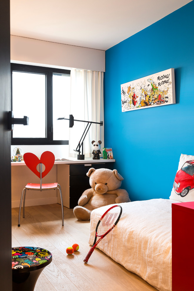 Diseño de habitación infantil unisex de 4 a 10 años actual de tamaño medio con escritorio, paredes azules y suelo de madera clara