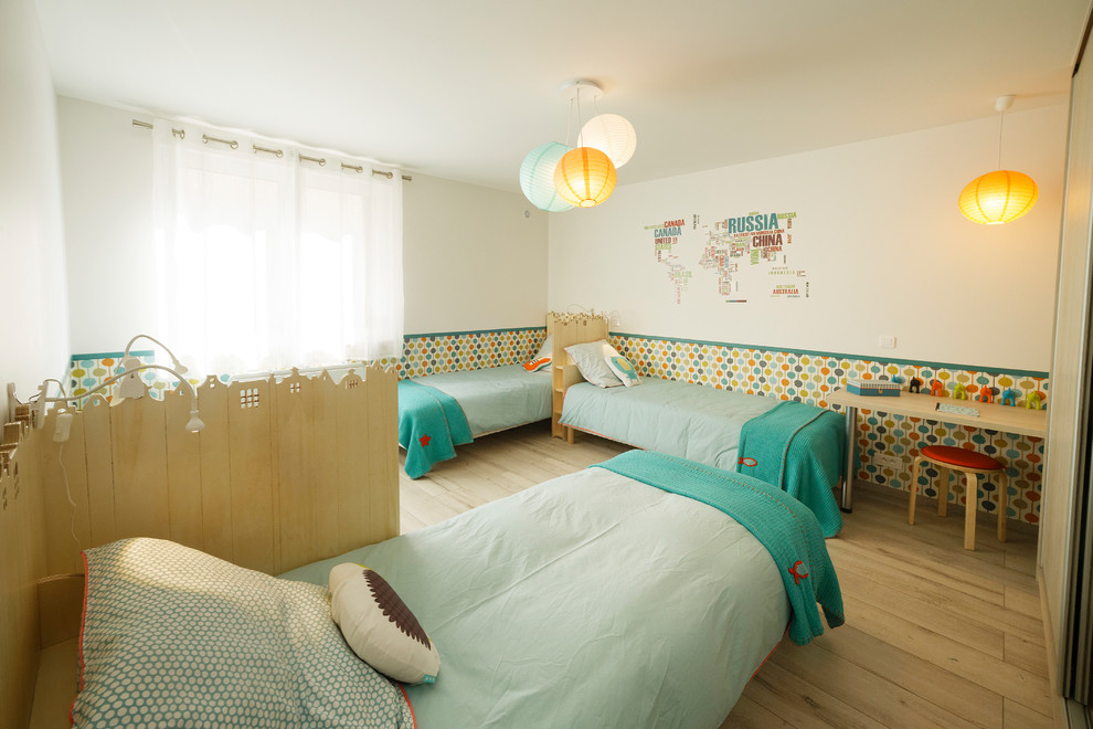 This is an example of a large scandi gender neutral children’s room in Toulouse with multi-coloured walls, light hardwood flooring and beige floors.