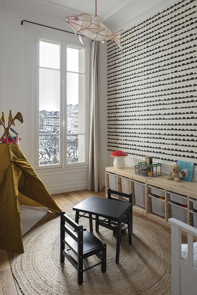 Inspiration for a traditional gender neutral playroom in Paris with white walls, medium hardwood flooring and brown floors.
