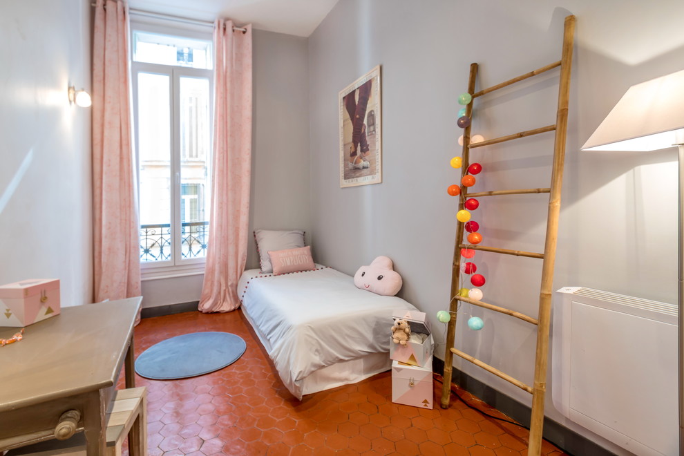 Cette photo montre une chambre d'enfant de 4 à 10 ans éclectique de taille moyenne avec un mur gris et tomettes au sol.