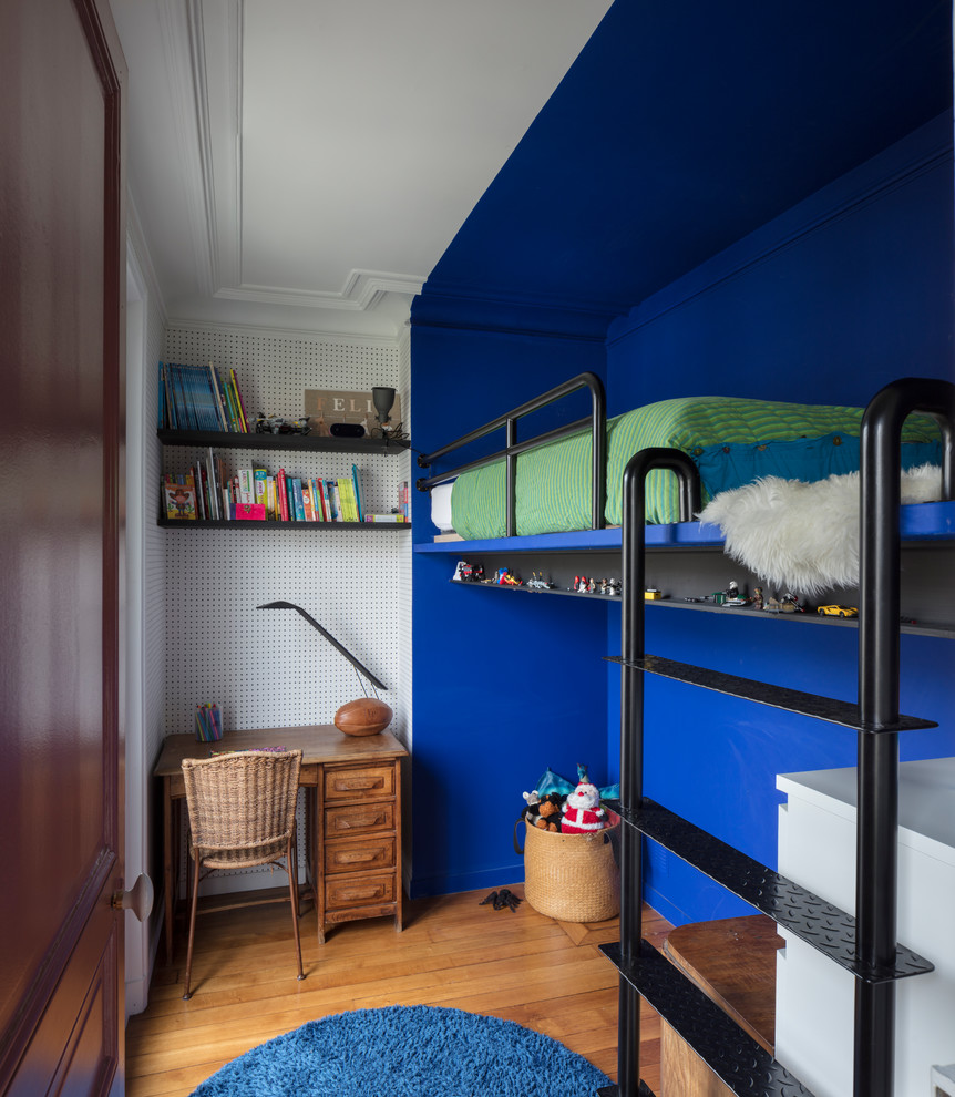 This is an example of a small contemporary gender neutral children’s room in Paris with blue walls, medium hardwood flooring and beige floors.