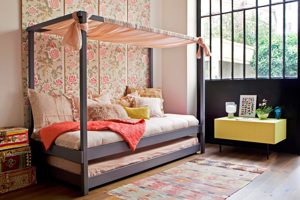 This is an example of a medium sized bohemian children’s room for girls in Paris with pink walls and medium hardwood flooring.