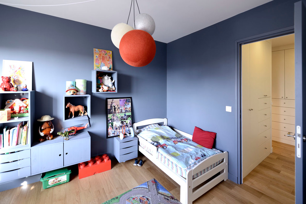 Cette photo montre une grande chambre d'enfant de 4 à 10 ans tendance avec un mur bleu et parquet clair.