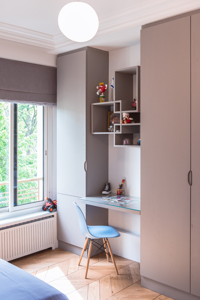 Idée de décoration pour une chambre de garçon de 4 à 10 ans design de taille moyenne avec un bureau, un mur blanc et un sol en bois brun.