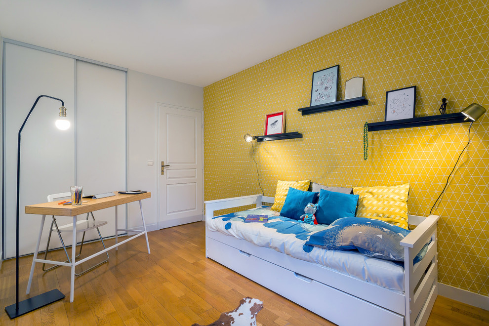 Réalisation d'une chambre d'enfant design avec un mur jaune, un sol en bois brun et un sol marron.