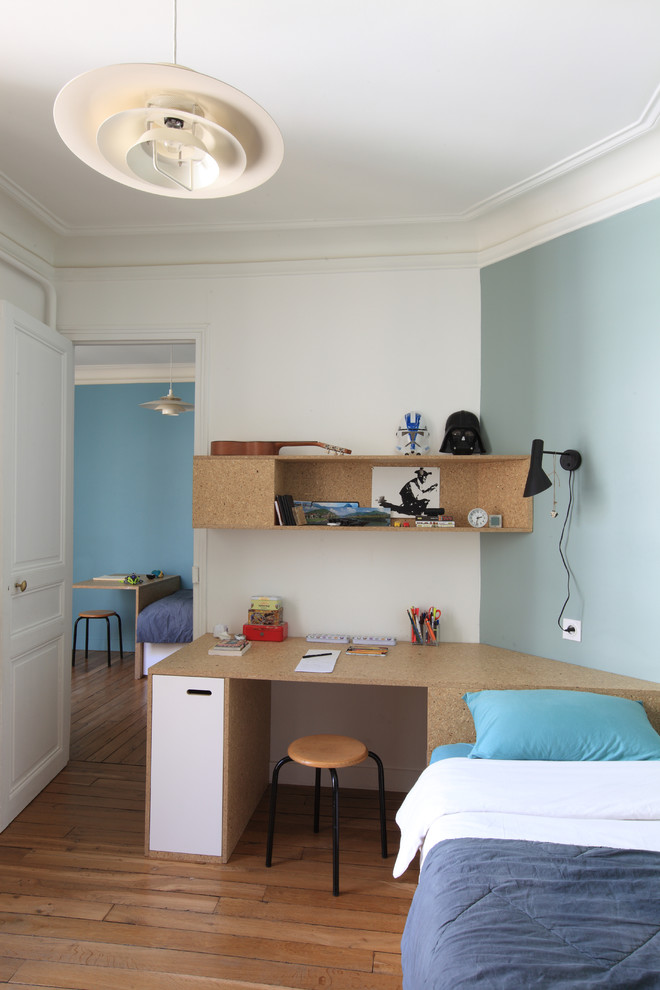 Ejemplo de habitación infantil unisex de 4 a 10 años actual de tamaño medio con escritorio, suelo de madera en tonos medios y paredes multicolor